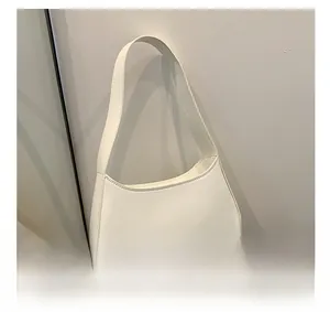 Close-up of cream white hobo underarm bag with fine stitching on a white round stool