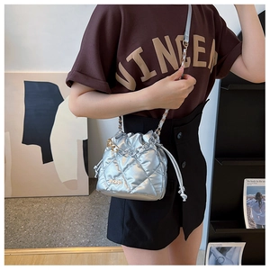 Close-up of silver quilted bucket bag featuring a chain strap and metal logo lettering