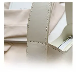 Detail showing the reinforced handle attachment and fine stitching on beige PU leather bag
