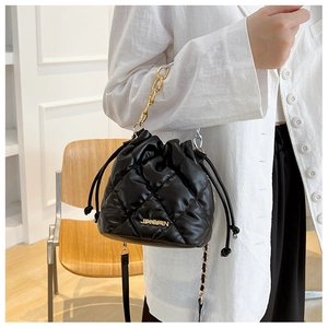 Detail of black quilted bucket bag with drawstring closure and gold chain strap