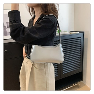 Detail view of a minimalist silver underarm bag with smooth metallic finish on model