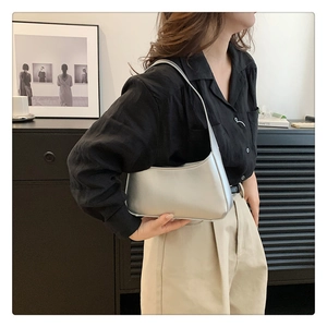 Close-up of metallic silver crescent underarm bag with glossy finish on shoulder strap