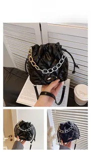 Detail of black quilted bucket bag with gold chain handle and drawstring closure