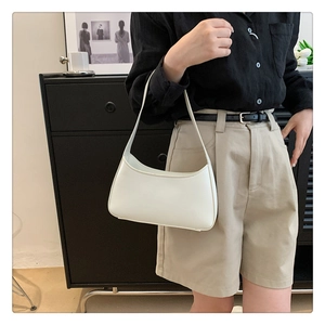 Modern white crescent underarm bag shown on a model with minimalist leather finish