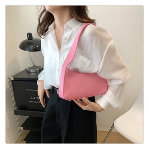 Close-up of pink minimalist hobo bag worn with a white shirt and black trousers