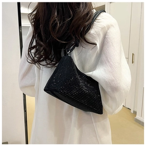 Detail shot of a black rhinestone handbag showing shimmering texture and shoulder strap fit
