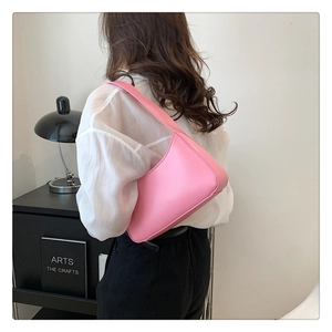 Side view of a pink minimalist Hobo underarm bag shown on a model's shoulder