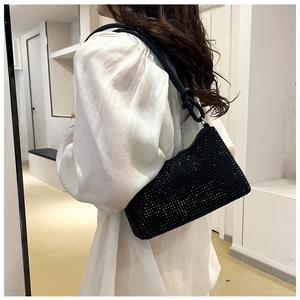 Detail of black rhinestone shoulder bag with elegant knot strap shown on model shoulder