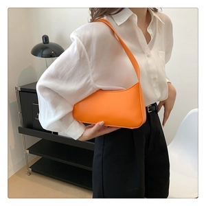 Close-up of bright orange minimalist crescent underarm bag with a wide strap for women