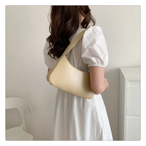 Minimalist beige matte leather underarm bag shown on shoulder for sizing and fit