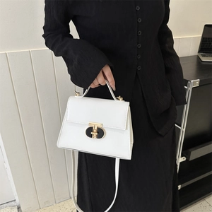 Elegant white leather crossbody handbag with gold clasp shown on a fashion model