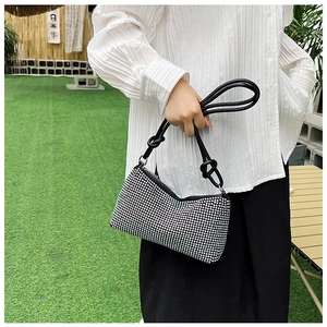 Detail of a sparkling rhinestone evening bag with elegant knot handle on green grass