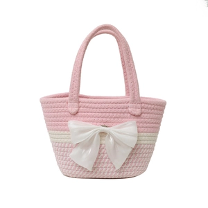 Pink and beige woven bucket tote bag featuring a large decorative white satin bow accent