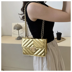 Detailed view of the gold quilted bag with metal chain strap worn by a model