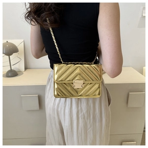 Detail of gold mirror finish crossbody bag with V-shaped quilting and chain strap
