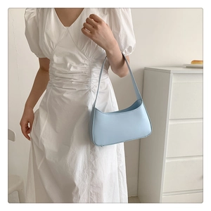Light blue faux leather half-moon shoulder bag worn by a model in a minimalist setting