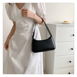 Detail of minimalist black underarm bag made of matte PU leather on a white background