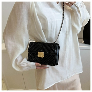 Close-up of black patent leather crossbody bag with V-quilt pattern and gold chain strap