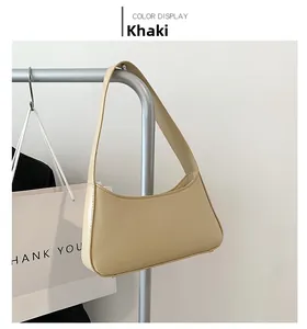 Detail view of khaki half-moon underarm bag displayed on a sleek metal rack