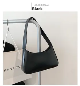 Minimalist black underarm bag hanging on a rack with a sleek matte finish and round edges