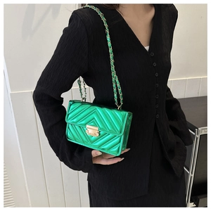 Close-up of emerald green quilted patent leather bag with gold hardware and chain strap