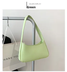 Close-up of a light green minimalist underarm bag with smooth texture and sturdy shoulder strap