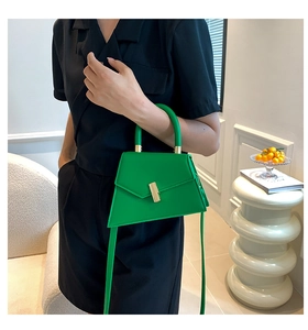Detail of emerald green trapezoid handbag with gold twist lock and smooth leather