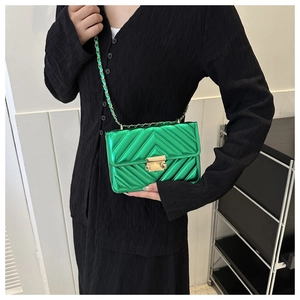 Detail of bright green patent leather crossbody bag with V-shaped quilting and gold chain