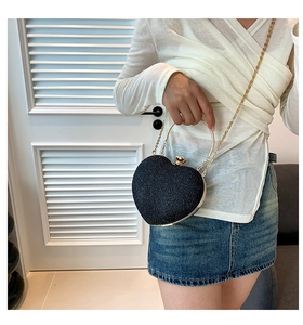 Detail of heart-shaped evening bag with black glitter finish and gold chain strap