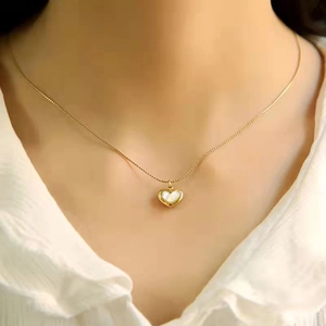 Collier minimaliste en or avec pendentif cœur en nacre blanche porté par un mannequin femme