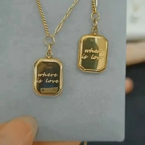 Details der goldenen rechteckigen Halskette mit graviertem Schriftzug und dunkler Emaille