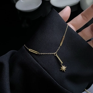 Titanium steel tassel necklace featuring a gold star pendant and chain links over black fabric