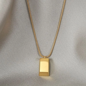 Minimalist gold bar pendant necklace with sleek snake chain on grey silk background