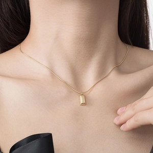 Minimalist gold bar pendant necklace with sleek snake chain shown on a female model