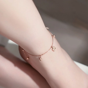 Makroaufnahme von Fußkette in Roségold mit vier kleinen Glocken und Kleeblatt-Anhänger