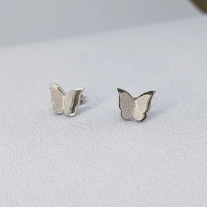 Macro detail of silver butterfly studs featuring matte glitter and mirror finish layers