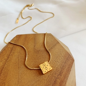 Golden titanium steel necklace with Double Happiness pendant on wooden display tray