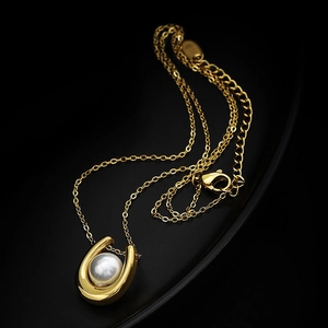 Collier élégant doré en forme de U avec perle blanche sur un plateau noir courbé