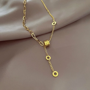 Elegant gold titanium steel hourglass necklace with engraved rings on purple satin background
