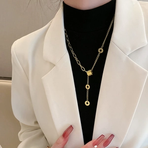 Golden Y-shaped tassel necklace with triple rings and engraving worn with white blazer