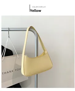 Detail view of a yellow minimalist crescent shoulder bag made of smooth synthetic leather