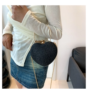 Chic black heart-shaped handbag with glitter finish and gold chain strap on a model