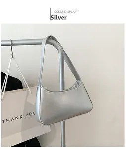 Detail view of a silver metallic hobo bag hanging on a rack in a minimalist studio setting