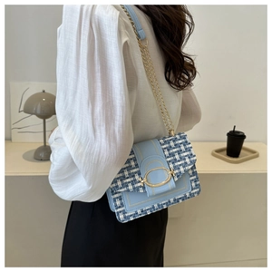 Close-up of light blue tweed crossbody bag featuring gold chain strap and metal clasp