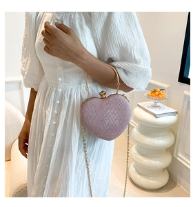Detail of heart-shaped evening bag in pink sequins with gold round metal handle