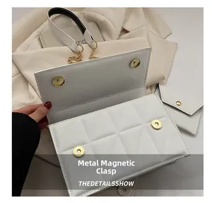 Detail der weißen Stepptasche mit goldenen Magnetverschlüssen und Leder-Kettenriemen
