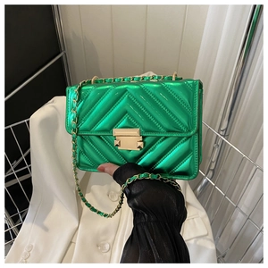 Close-up of green quilted leather bag with V-stitch pattern and gold metal twist lock