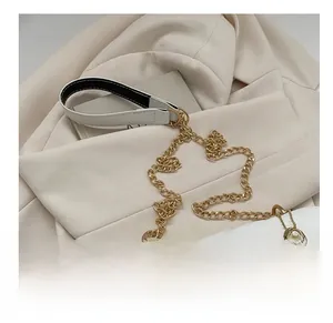 Detailansicht des weißen Leder-Schultergurts und der goldenen Metallkette der Handtasche