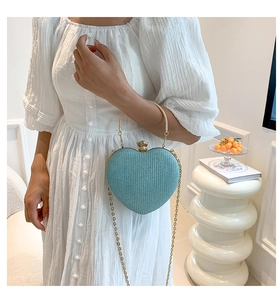 Detail view of heart-shaped blue evening clutch with gold ring handle and chain