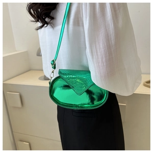 Détail du sac bandoulière ovale vert métallisé avec texture croco et boucles dorées